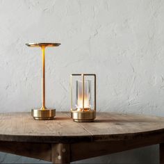 a table with two candles on it and a light in the middle next to it