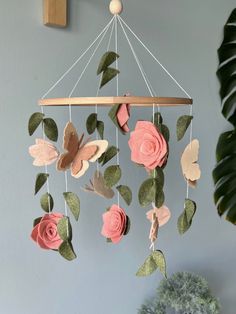 a pink rose and butterfly mobile hanging from a wall