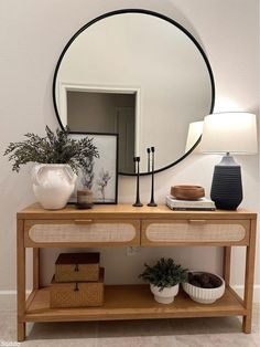 a wooden table topped with a mirror and two potted plants on top of it