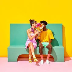 two people sitting on a bench with flowers