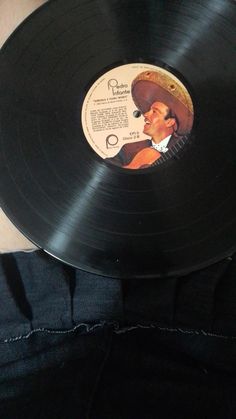 a person holding up a black record with an image of a man wearing a straw hat