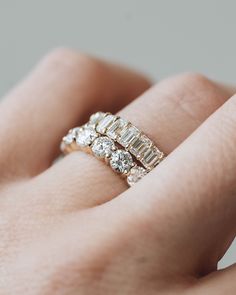 a woman's hand with a diamond ring on top of her finger and an engagement band in the middle