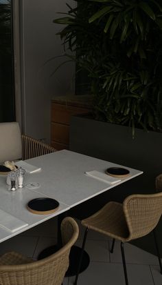 the table is set with place settings for two people to eat at, and there are plants in the background