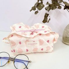 a pair of glasses sitting on top of a white table next to a pink polka dot bag