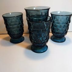 four blue glass vases sitting next to each other