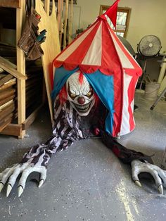 a creepy clown is sitting under a tent