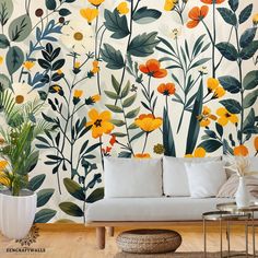 a white couch sitting in front of a wall covered in yellow and orange flowers on it