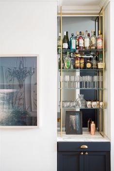 an open cabinet filled with liquor bottles and other items on top of a white wall