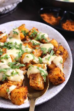 a white plate topped with tater tots covered in cheese and cilantro