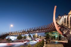 a very tall metal structure next to a street with cars passing by on the road