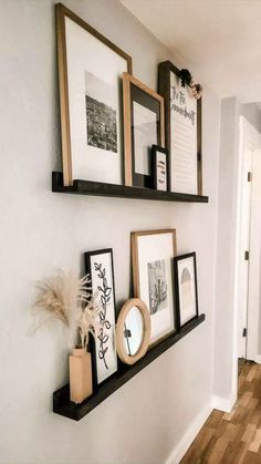 three black and white frames are hanging on the wall next to a wooden flooring