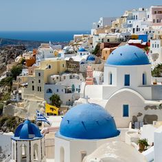 blue and white buildings on the side of a hill with water in the back ground