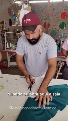 a man is cutting fabric with scissors on a table