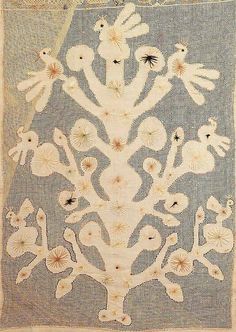 an embroidered piece with white flowers and birds on blue fabric, in the shape of a tree