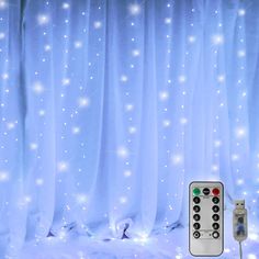 a remote control sitting in front of a curtain with white lights on it's sides