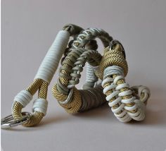 several bracelets are stacked on top of each other with gold and white cords attached to them