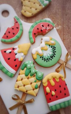 some decorated cookies are sitting on a tray with ribbons and bows around the top one is watermelon, pineapple, kiwi