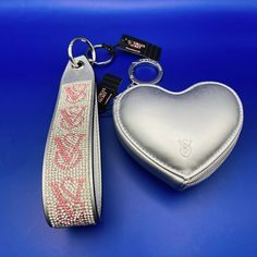 a silver heart shaped keychain with a pink and white design on the front