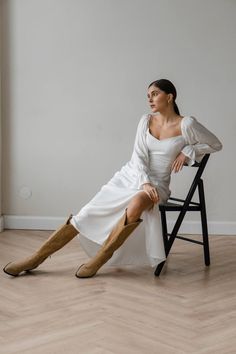 a woman is sitting on a chair and posing for the camera with her legs crossed