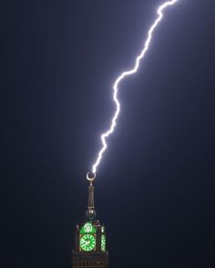 a clock tower with a lightning bolt coming out of it's side and the sky in the background