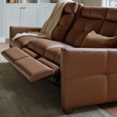 a brown leather reclining couch in a living room with two pillows on the back