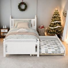 a white bed sitting next to a christmas tree