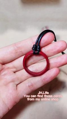 a person holding a red ring in their hand with the words you can find those cords from my online shop