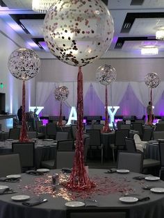 a room filled with lots of tables covered in silver and red confetti balls