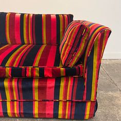 a colorful striped couch sitting on top of a cement floor next to a white wall