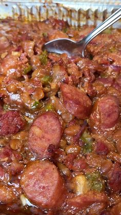 a close up of a plate of food with sausage and beans in sauce on it