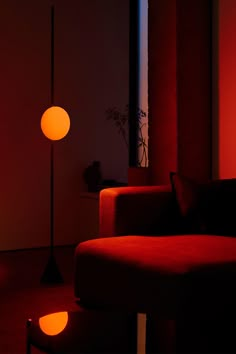 a red couch sitting next to a lamp in a living room