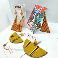 three pieces of art work are displayed on a table with greeting cards and earring sets