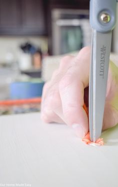 a person cutting carrots with a sharp knife on a counter top in a kitchen