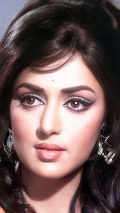 a close up of a woman with long dark hair and large earrings on her head