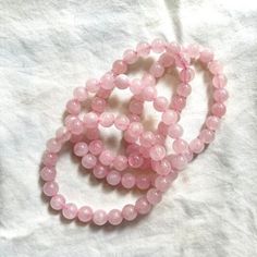 two pink beads are on a white sheet and one is in the shape of a circle