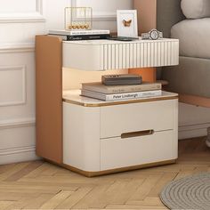 a nightstand with books on top of it next to a bed