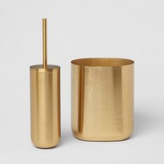 a gold container with a toothbrush in it next to a cup that has a straw sticking out of it