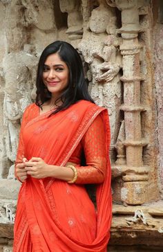 a woman in an orange sari poses for the camera