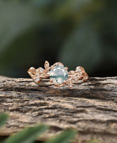 a close up view of an engagement ring on top of a tree branch with leaves