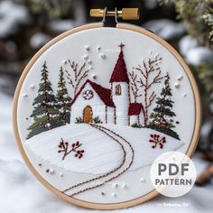 a cross stitch christmas ornament with a church in the snow