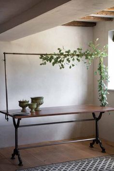 a table with two vases on it in front of a window and a rug