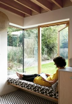 a woman sitting on a window sill reading a book