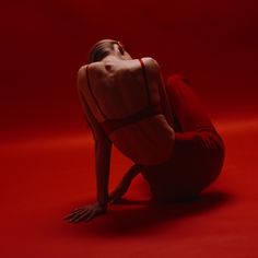 a woman sitting on the ground with her head in her hands and arms behind her back