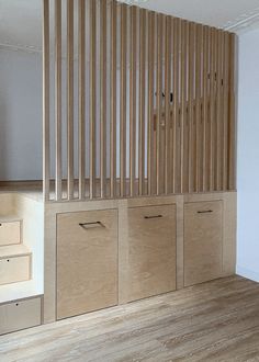 an empty room with wooden stairs and storage boxes on the wall, in front of white walls