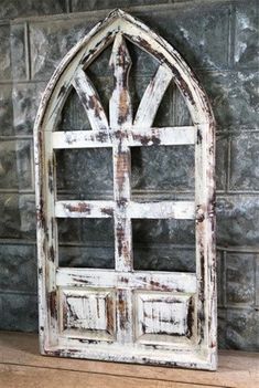 an old white window frame sitting on top of a wooden table next to a brick wall