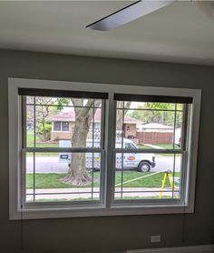 an empty room with two windows and a tree in the window sill on the far side