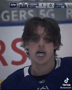 a young man with glasses on his face is standing in front of a hockey sign