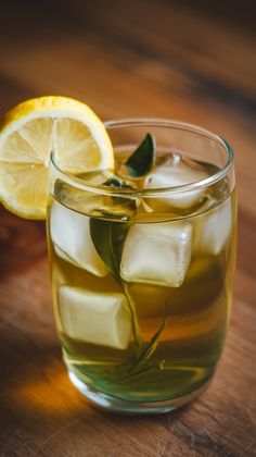 a glass filled with ice and lemon on top of a wooden table