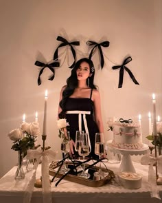 a woman standing in front of a table with cake and wine glasses on top of it