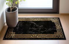 a black and gold rug with a potted plant on the floor next to it